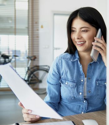 Cheerful Asian woman in the office talking on the phone